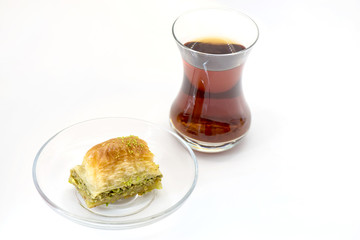 Baklava with pistachio and turkish cup of tea on a white background