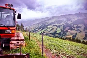Naklejka premium alpine mountain under a foggy sky with a excavator in the foreground in Saalbach, Austria