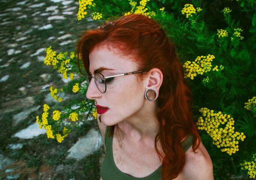 Mujer joven con gesto de tristeza posando junto a flores amarillas 