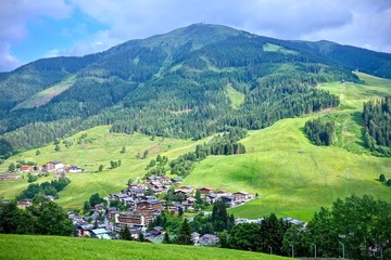 Fototapeta na wymiar lush green alpine peak under a blue cloudy sky in Saalbach, Austria