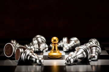 single gold pawn chess surrounded by a number of fallen silver chess pieces , business strategy...