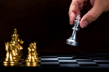 business man moving silver king chess figure to the board , fight with gold chess team , business...