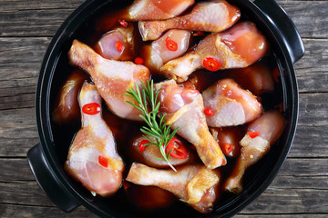 raw chicken drumsticks in a black pot