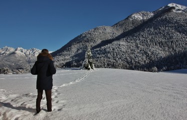 Man in winter coat watching the snowy alpine landscape in Bondo, Trentino Alto Adige, Italy