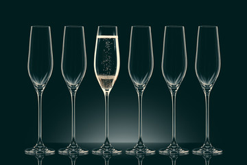five empty glasses and one glass with champagne on black