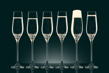 six transparent glasses with champagne on black