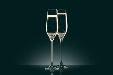 two transparent glasses of champagne on black