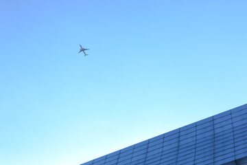 Fototapeta na wymiar Airplane flying above glass office buildings and futuristic design