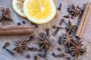 Star anise, orange frut slices, cinnamon and cloves on wooden table.