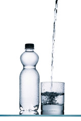 wet plastic bottle and water pouring into glass isolated on white