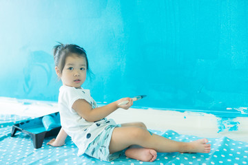 3 years old girl painting the wall at home.