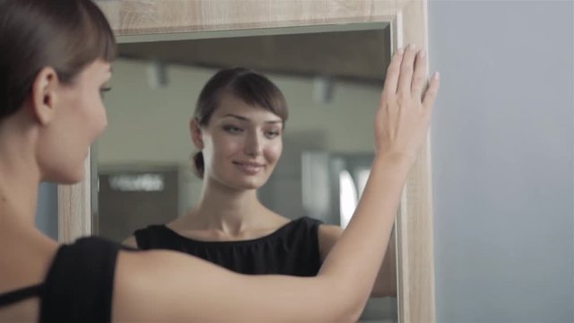 Pretty girl making makeup in bathroom look on mirror. Woman take care about look. Looking into a mirror. Gorgeous woman in dress model go to party