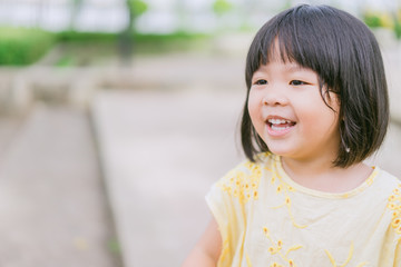 Little asian girl smiling with perfect smile and white teeth in a park and looking at camera.Little girl child showing front teeth with big smile.Joyful portrait of asian elementary school student.