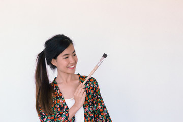 Fashion Portrait of Young cute asian woman wearing floral robe and holding paint brush