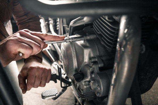 Fototapeta Close up of man's hand fixing motorcycle