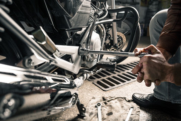 Fototapeta premium Close up of man's hands with motorcycle in garage