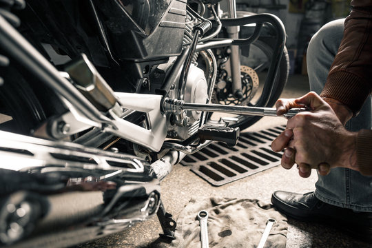 Close up of man's hands with motorcycle in garage