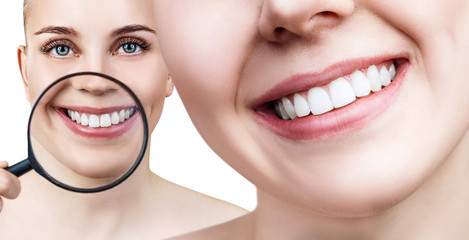 Woman with magnifying glass shows white teeth.