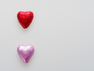 Heart shape chocolate wrapped in red and pink foil isolated over white background