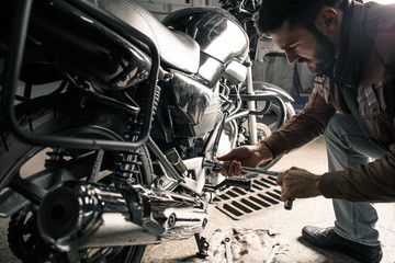 Young handsome man repairing motorcycle