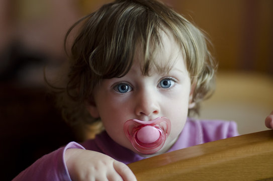 cute baby girl with a soother in her mouth