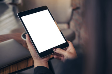 Mockup image of woman's hands holding and looking at black tablet pc with blank white desktop screen in cafe