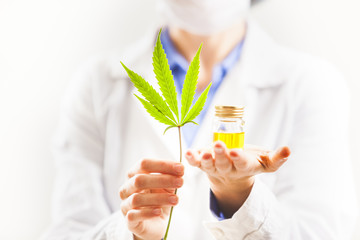 Woman doctor holding cannabis leaf and oil