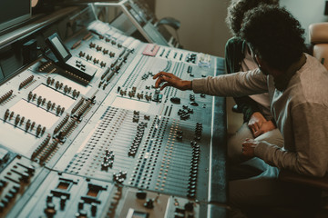 modern musicians working with graphic equalizer at recording studio