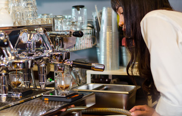 Girl barista bartender waiter in uniform making coffee at the bar