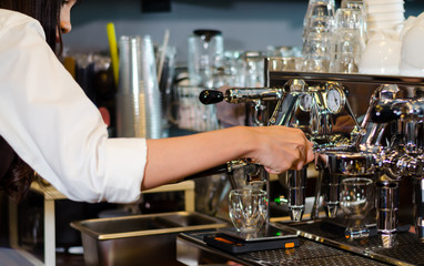 Girl barista bartender waiter in uniform making coffee at the bar