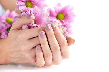 Hands of a woman with pink manicure on nails and pink flowers