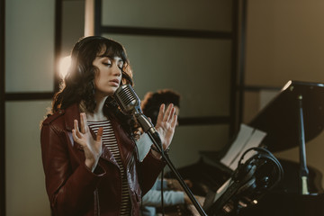 beautiful young female singer performing song with pianist blurred on background