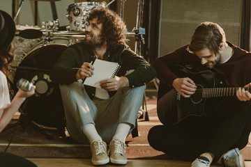young music band sitting on floor with notepads and talking