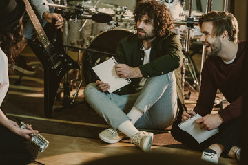 music band sitting on floor with notepads and talking