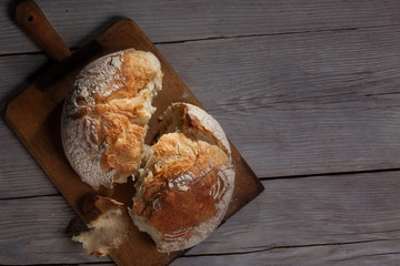 Torned homemade bread loaf on old cutting board with a free space on the right