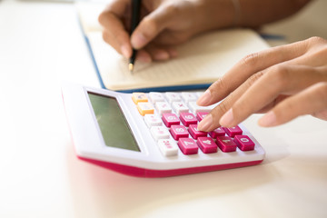 Close up accountant or banker marketing calculations and note data to notebook paper. Concept finances and economy savings.