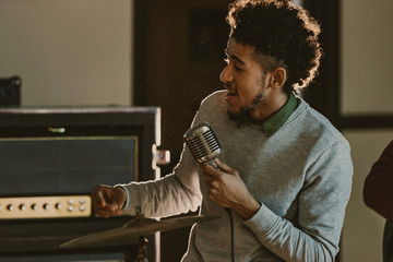 handsome african american singer performing song with microphone