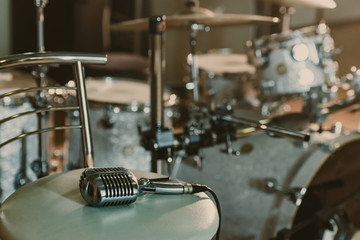 Vintage microphone lying on chair in front of drum set