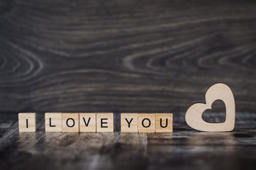 the phrase I love you wooden cubes and a wooden heart on a dark wooden background