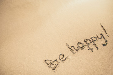 Be Happy text written on the sand