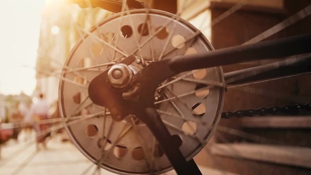Closeup slow motion footage of spinning vintage bicycle wheel on street at sunset