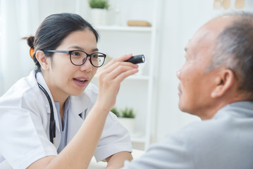 Fototapeta premium Female Doctor checking to senior man patient eyes.