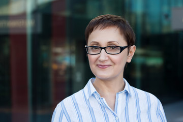 Older business woman headshot. Close-up portrait of executive, teacher, principal, CEO. Confident and successful middle aged woman 40 50 years old wearing glasses and shirt and smiling - 187477369