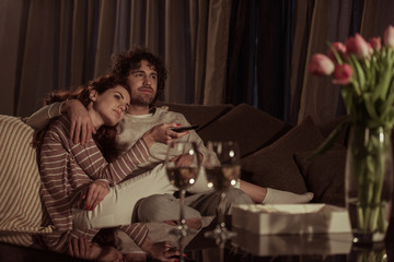 heterosexual couple watching tv on sofa in evening