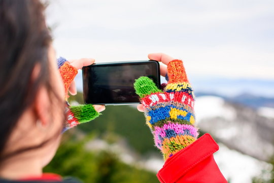 Girl taking picture of winter scenery with a smart phone
