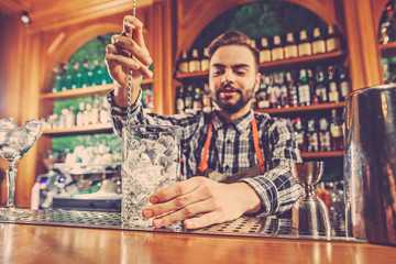 Barman making an alcoholic cocktail at the bar counter on the bar background