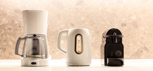 Kitchen small appliances on white surface. Colorful, blurred background. Close up view with details.