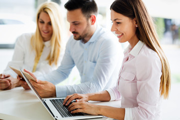 Naklejka premium Three young smiling colleagues working together on laptop