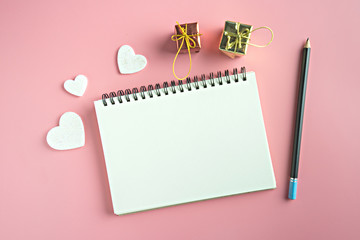 Top view of blank notebook pencil and hearts on pink background with copy space.