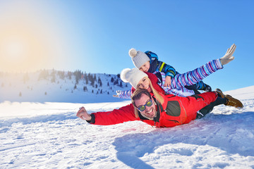 Fototapeta na wymiar happy young family playing in fresh snow at beautiful sunny winter day outdoor in nature